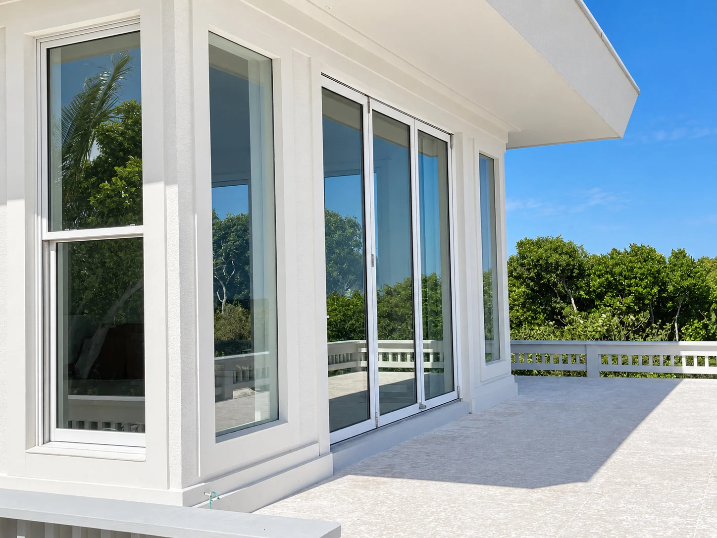 Closed white framed glass doors along a sunny contemporary home terrace