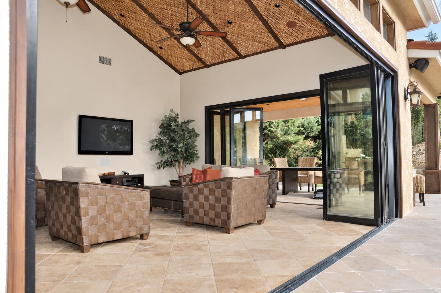 Wide folding door opening with panels stacked beside a sitting room that opens to the outdoors