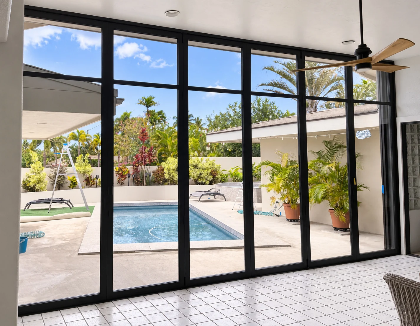 Tall dark bronze glass door panels with midrails overlooking a tropical pool