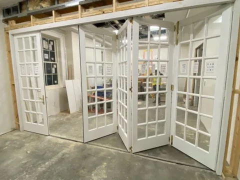 A wood folding-door system with divided lites, partly folded open.