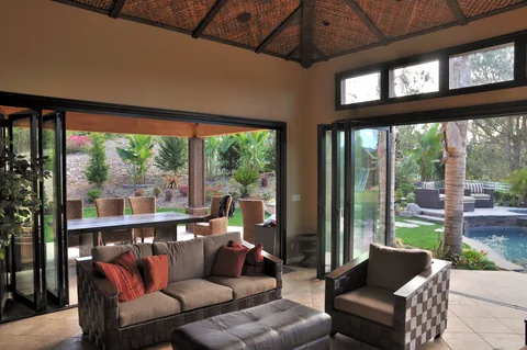Dark aluminum glazing around a living space overlooking a garden.