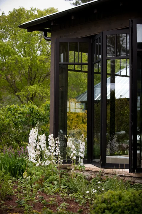 Tall dark folding doors along a landscaped event pavilion.