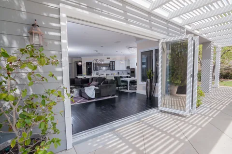 An exterior view of a screened opening beneath a pergola.