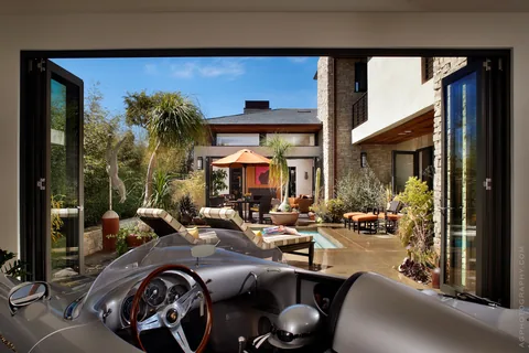 Open folding doors connecting a garage lounge to the courtyard.