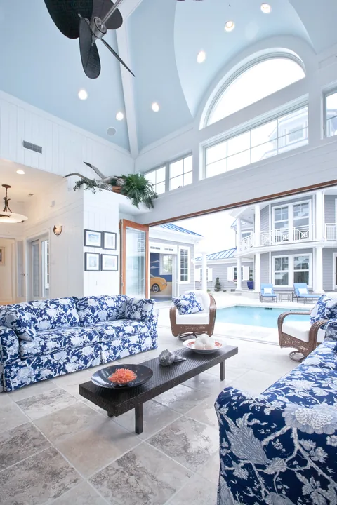 A tall living room with white clad folding doors and arched glazing.