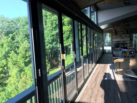 Dark aluminum folding doors enclosing a wooded deck.