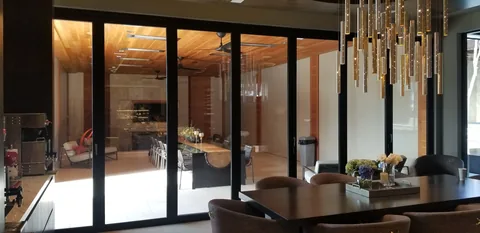 An interior view through aluminum folding doors toward terrace seating.