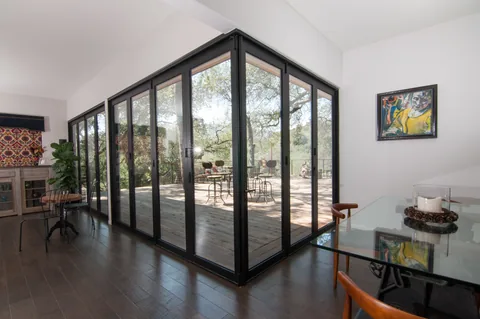 Closed standard aluminum corner doors between a dining room and wooded deck.