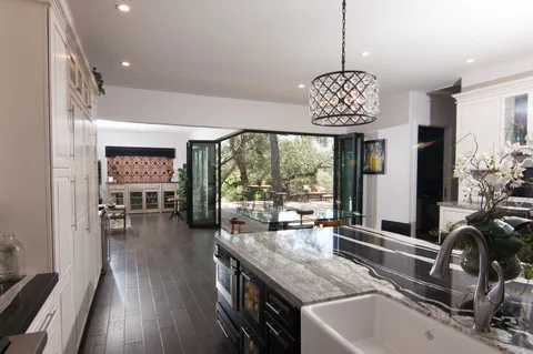 View from the kitchen through open corner doors to an outdoor dining deck.