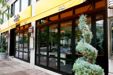 Dark folding glass doors beneath a restaurant awning.