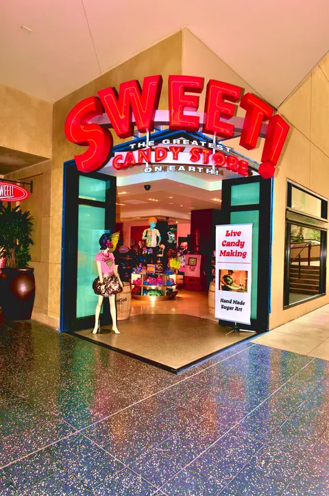 Sweet candy-store entrance with aluminum zero-post corner doors folded open.